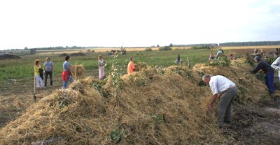 Участники семинара учатся делать холмистую гряду. Трактор  вырыл колею глубиной полметра, в нее заложили бревна, ветки, картон. Сверху засыпали землей, создав холм-трапецию высотой до полутора метров. По бокам уложили чернозем, перевернутый дерн, сверху мелкие ветки и солому. Гряда готова, можно высаживать на нее всевозможные растения. Солома сохраняет тепло, влагу, препятствует росту сорняков. Бревна в земле притягивают влагу, гниют и дают тепло корням растений. 
